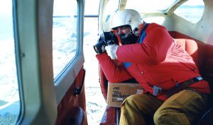 Lloyd Homer in action, taking photos out of the open door of a Cessna. Photo: Alan Knowles